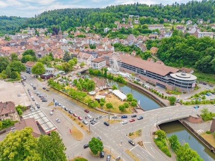 Wide view of a town with river and Ferris wheel in the middle of a green and mountainous