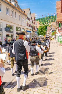 Brass musicians march through a lively village street in sunny weather, 950 years of Calw, Calw