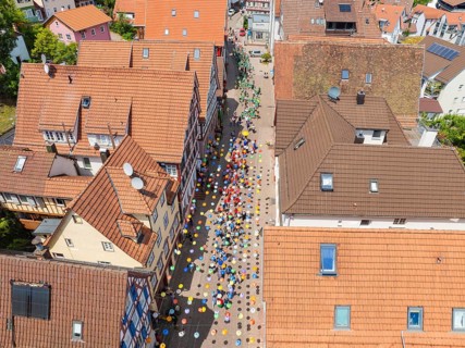 People walking on a street decorated with colourful umbrellas, 950 years Calw, parade Calw, Black