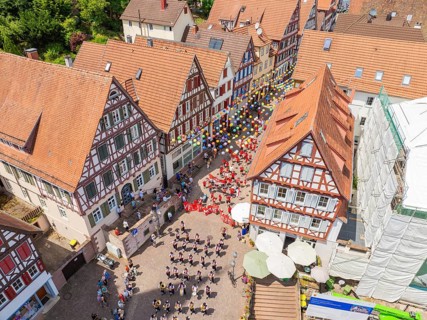 From above you can see people in formation and colourful balloons next to historic house facades,