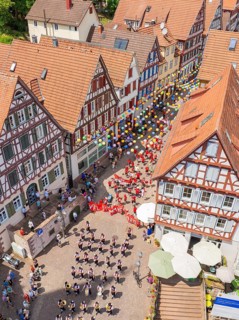 A colourful event with lots of balloons and people between historic half-timbered houses, 950 years