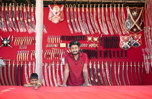 Indian man and boy at a market stall for weapons in the Thar Desert or Great Indian Desert, near