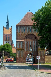 Brick building Anklamer Tor, St Mary's Protestant Church at the back, town of Usedom, island of