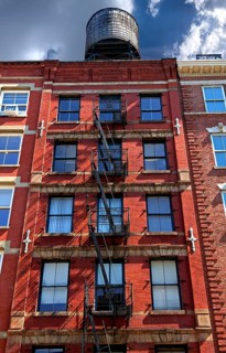 Residential building with fire escapes and wooden water tank on the roof, Downtown NY, New York