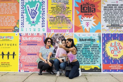 Festival visitors taking photos of themselves in front of Lollapalooza Festival posters from