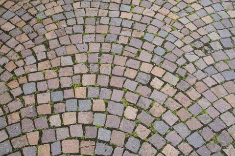 Intertwined cobblestones in an arched pattern, dominant colours are grey and pink, cobblestones,