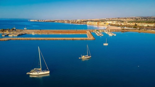 Stunning aerial view of sailboats floating on calm blue water near the coastline of torrevieja