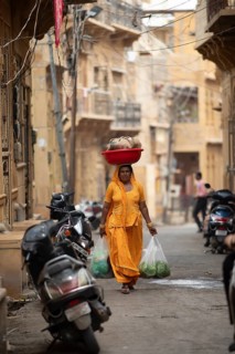 Indian woman carrying a bowl on her head in the old town of Jaisalmer, Rajasthan, India