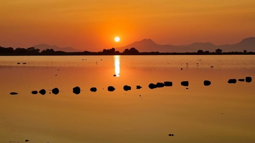 Dramatic sunset over a calm lake with mountain silhouette, salt lake, Tigaki, nature reserve, hydro