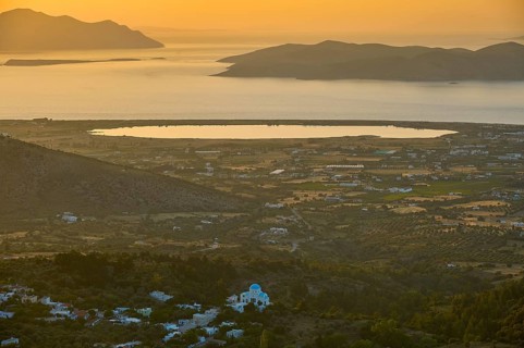 A view of a village and fields in front of the sea at sunset, salt lake, Tigaki, nature reserve,