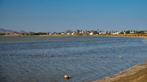 A coastal village on the shore of a lake in calm weather under a blue sky, salt lake, Tigaki,