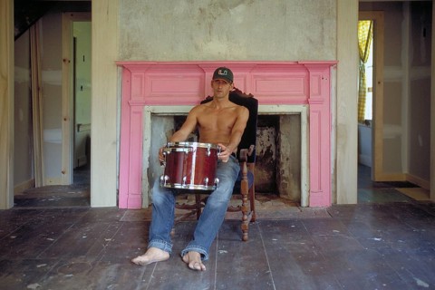 Young man with his drums in an empty room in front of a fireplace, New Jersey, USA