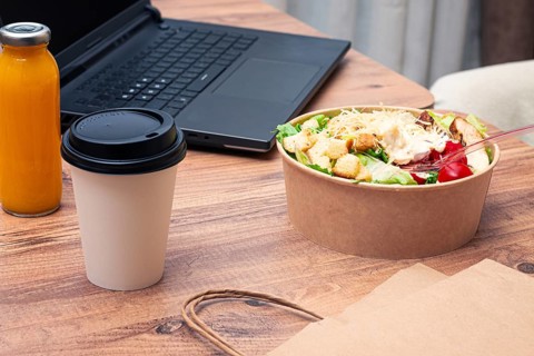 Work at home on a laptop, there is food on the table, salad, coffee and juice, delivery, there are