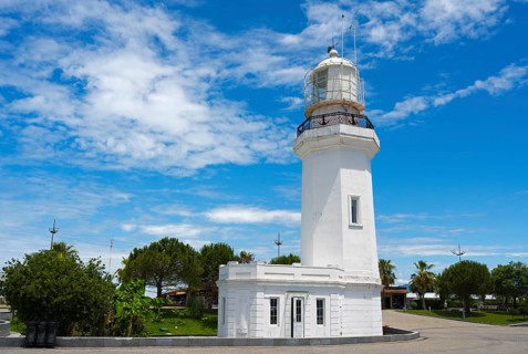 White lighthouse against a cloudy sky surrounded by palm trees and a road, lighthouse, Batumi,