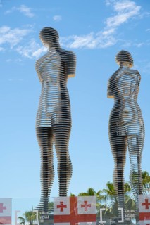 Metal figures of a woman and a man against a blue sky, Georgian flags at the bottom of the picture,