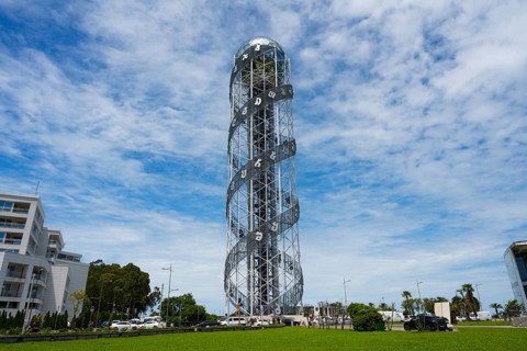 Large steel tower with spiral architecture against a slightly cloudy sky, Alphabetic Tower,