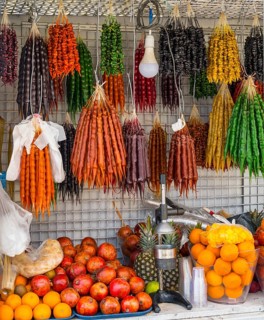 A market stall full of colorful fruits and traditional sweets with a juicer in the foreground,