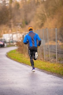 Man running on asphalt road wearing blue and black sportswear, triathlon, Calw, Germany