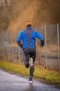 Back view of a runner on a country road wearing blue and black running clothes, triathlon, Calw,