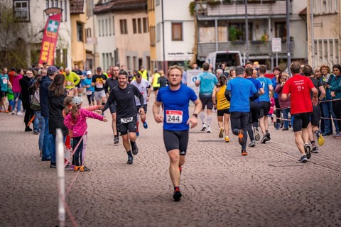 Runners and spectators on a paved road during a road race, triathlon, Calw, Germany