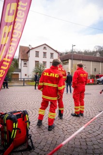 DLRG personnel wearing red uniforms stand on a paved square in front of buildings, Triathlon, Calw,