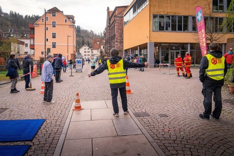 Group of people wearing safety vests at a roadblock in an urban environment, triathlon, Calw,