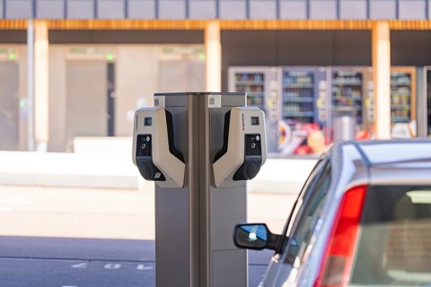 Detailed view of an electric vehicle at a charging station in front of parking lots, e-charging