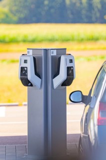 Electric car at a double charging station in a parking lot with a view of nature, e-charging park,