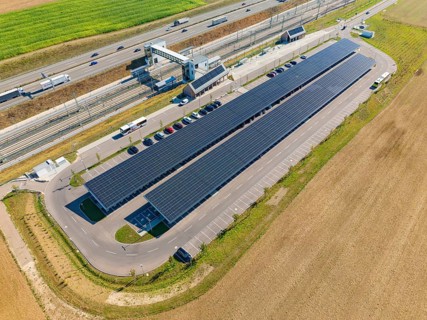 Solar system with parking spaces next to a well-traveled motorway and fields, e-charging park,