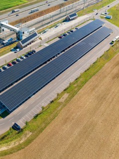 Solar system with adjacent parking spaces and parked cars under clear skies, e-charging park,