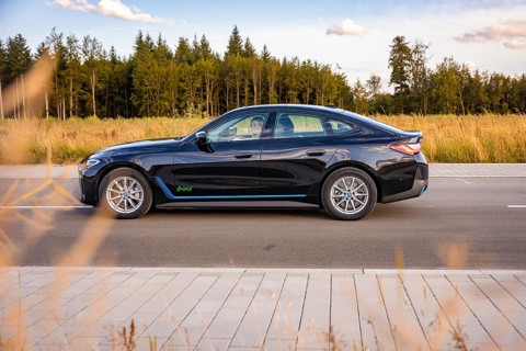 Black car on a road next to a field and forest under a blue sky, BMW i7 electric car, Deer E-