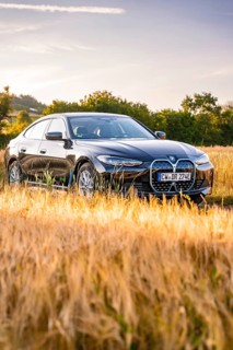 Black electric car in a cornfield at sunset, surrounded by a golden evening mood, BMW i7 electric