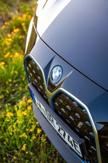Close-up of the front of a car with visible brand logo on a flowery meadow, BMW i7 electric car,