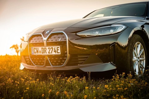 Front view of a BMW with grille and sunset in the background, BMW i7 electric car, Deer