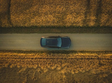 Aerial view of a car on a path between golden fields at sunset, BMW i7 electric car, Deer
