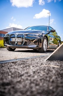 A black car is parked on a quiet road under a blue sky, BMW i7 electric car, Deer E- Carsharing,