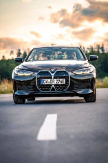 A black car on a country road at sunset with trees in the background, BMW i7 electric car, Deer