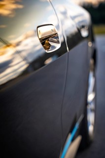 Close-up of a car door with sunset reflections on the paint, BMW i7 electric car, Deer