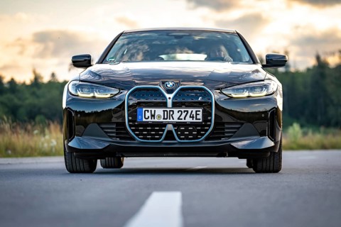 Front view of a black car on the road in front of a forest at sunset, BMW i7 electric car, Deer