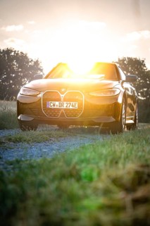 BMW with headlights switched on in the back light of sunset, BMW i7 electric car, Deer