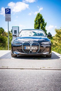 A black car is parked at a charging station with clear blue sky, BMW i7 electric car, Deer