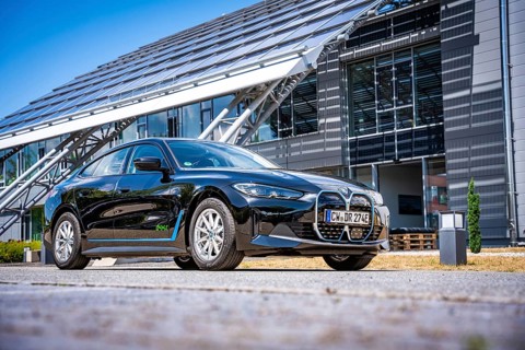Black car next to a modern building with solar panels and clear sky, BMW i7 electric car, Deer