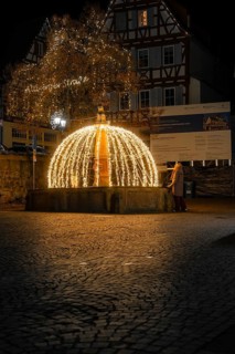 Atmospheric illuminated fountain at night in a paved old town scenario, Calw, Black Forest, Germany