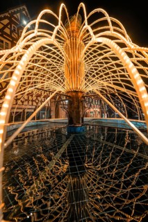 Artistic view of an illuminated fountain with detailed water reflections at night, Calw, Black