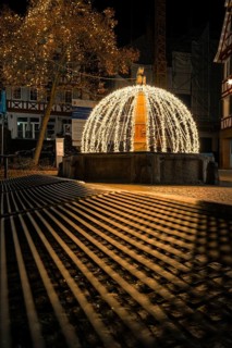 Atmospheric night view of a festive fountain with lights and shadows in an old town, Calw, Black