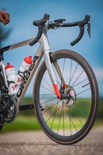 Front view of a racing bike with two water bottles standing on a country road under blue sky,