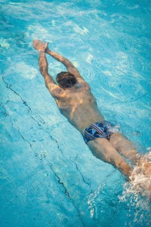 A diver in the pool shows dynamic underwater movements with splashing water, Triathlon, Calw,