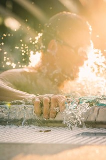 Close-up of a swimmer whose hand dynamically touches the water, light reflections, triathlon, Calw,