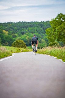 Cyclists in the distance on a winding country road surrounded by green countryside, Triathlon,