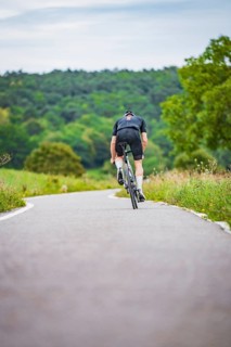 Cyclist climbing a road in hilly countryside surrounded by greenery, triathlon, Calw, Germany